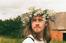Ein junger Mann mit einem Kranz aus Wiesenblumen / ***