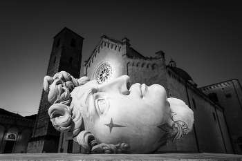 Irises. Open-air art in Tuscany. / Shot at the first light of the morning of the central square of Pietrasanta where every year works by artists from all over the world are temporarily exhibited. In the photo, front view of the tattooed David by the famous artist under the rose window of the Duomo.