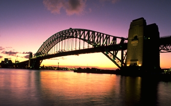 Sydney Harbour Bridge / The Harbour Bridge is as classic a symbol of Sydney as the shells of the Opera House itself.
Sydney Harbour Bridge, seen here at sunset, connects the Sydney central business district with the North Shore commercial and residential areas.
When completed, in 1932, the bridge Down Under was the widest bridge on the planet and the world's largest single-arch bridge; but was not the longest.
The single arch design was built from both ends (using cable supports) and joined in the middle.
Built to carry motor vehicles, trains, trams (until 1958), pedestrians and bicycles, the bridge's span of 1,650 feet allows unobstructed passage for ships in Sydney Harbour.
https://travelnotes.org/pics/Australia/05-Sydney_Harbour_Bridge.htm