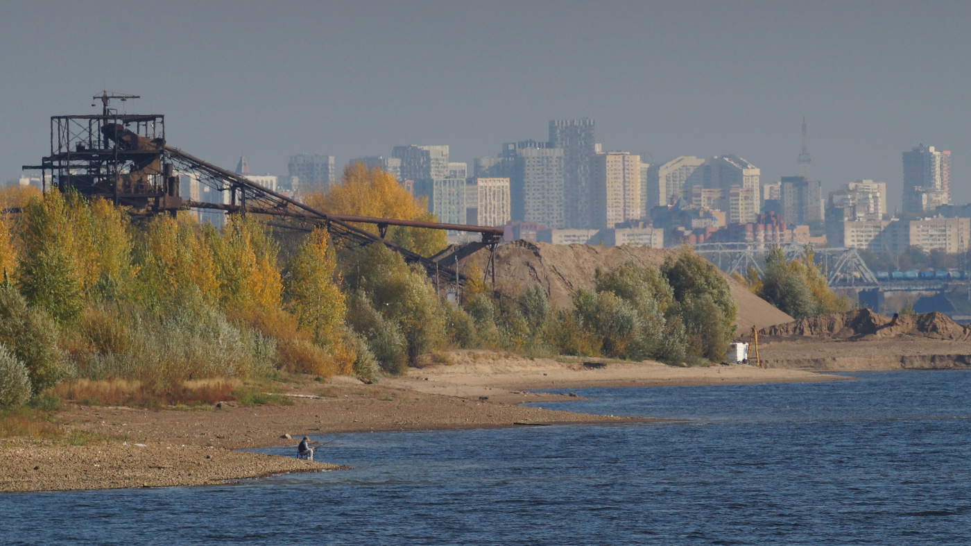 Осенний пейзаж с рыбаком на фоне города.