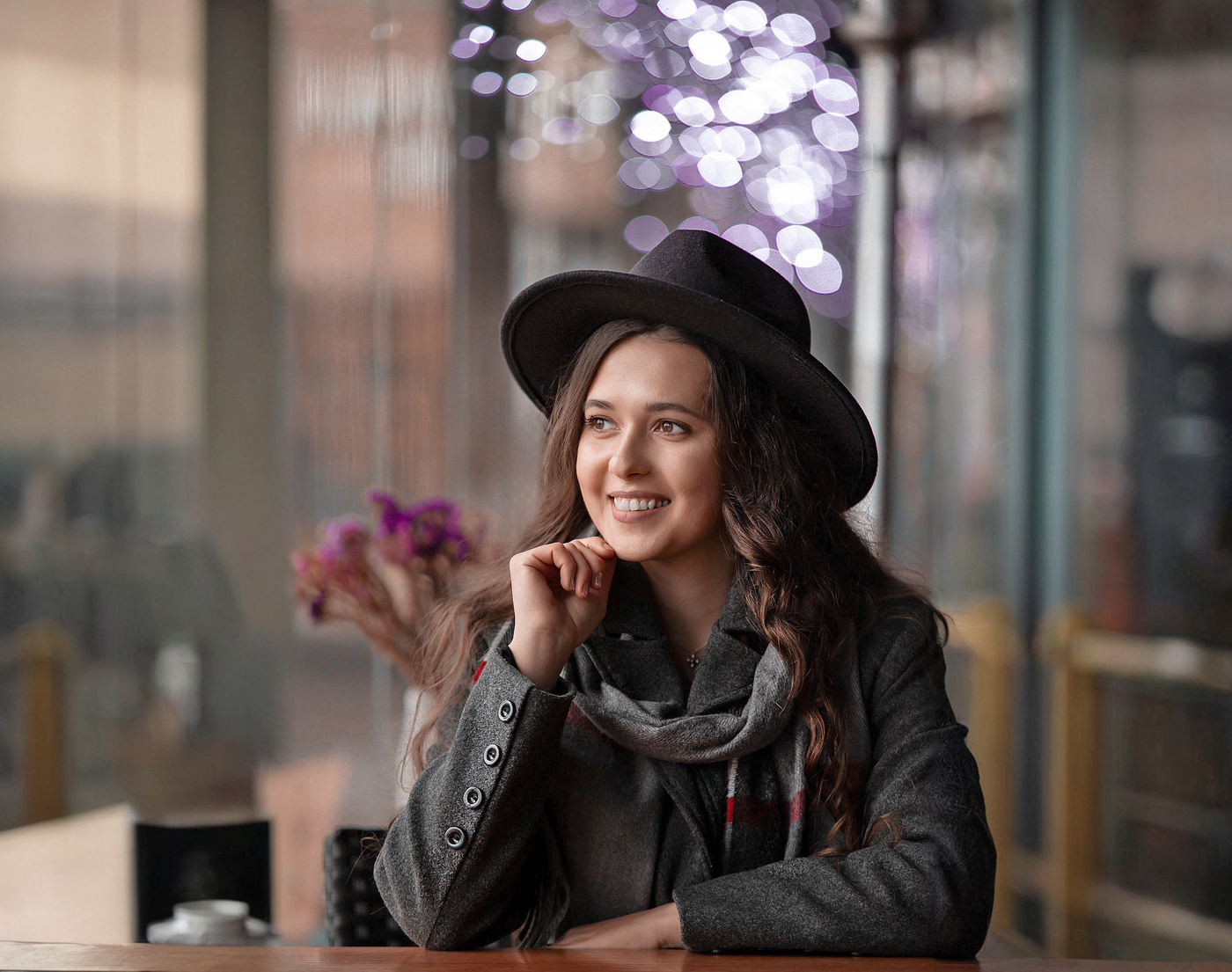 Девушка в шляпе за столиком в кафе.