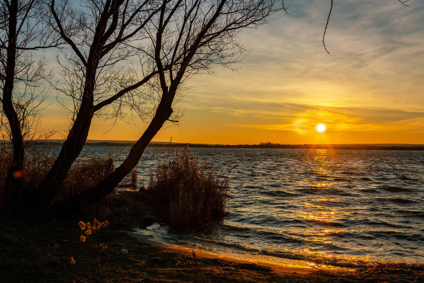 Над водой закат играет красками.