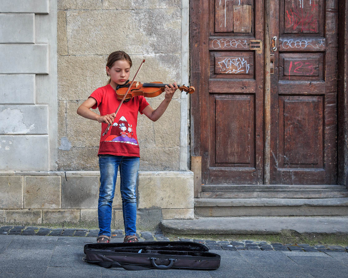 Сердитая чумазая девочка играет на скрипке