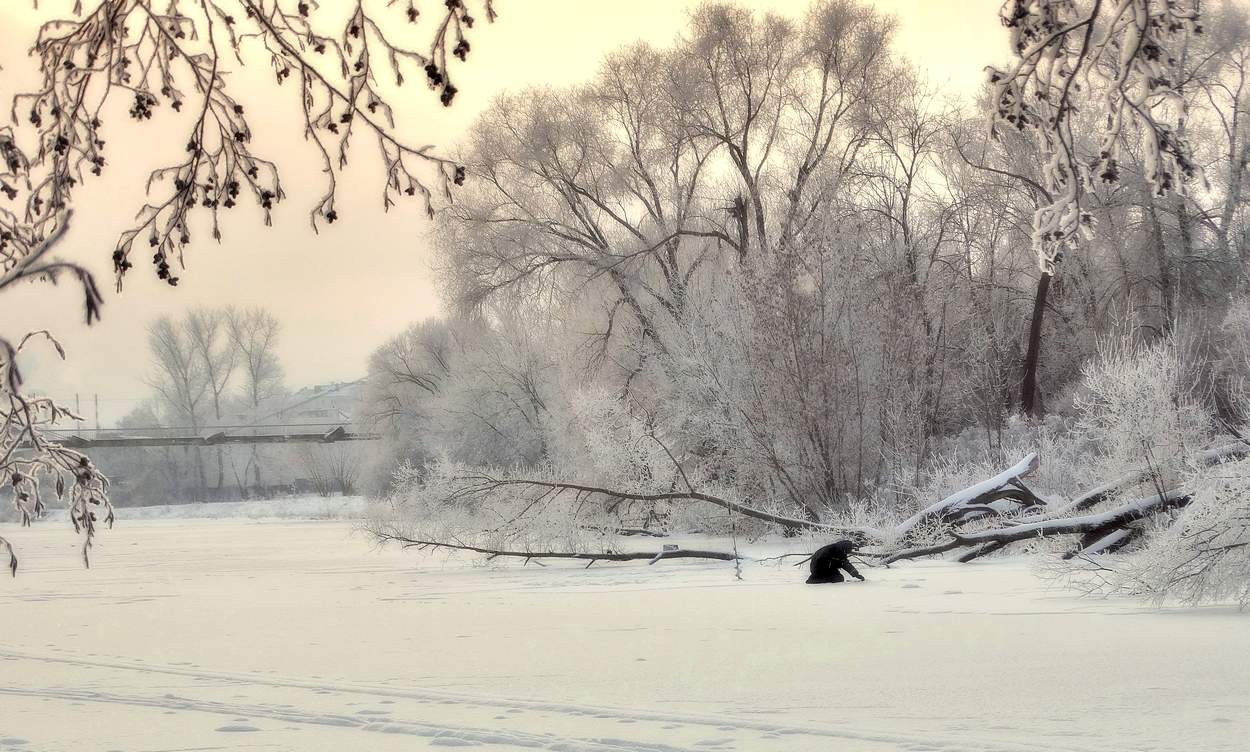 Зимним утром первый рыбак на льду реки